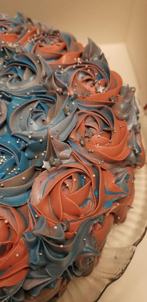En kake med blå og rosa glasur blomster dekor som dekker hele kaken