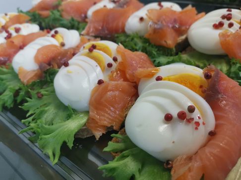 Et brett med påsmurte smørbrød med salat, røyket laks og kokt egg