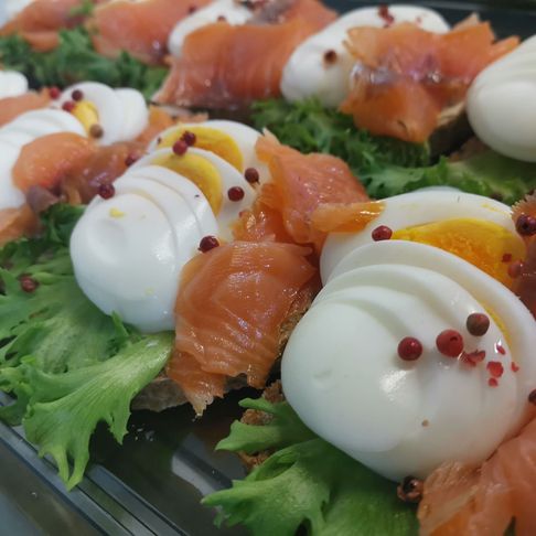 Et brett med påsmurte smørbrød med salat, røyket laks og kokt egg